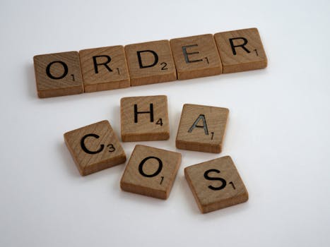 Scrabble tiles spelling 'ORDER' neatly lined up and 'CHAOS' jumbled on a white surface.